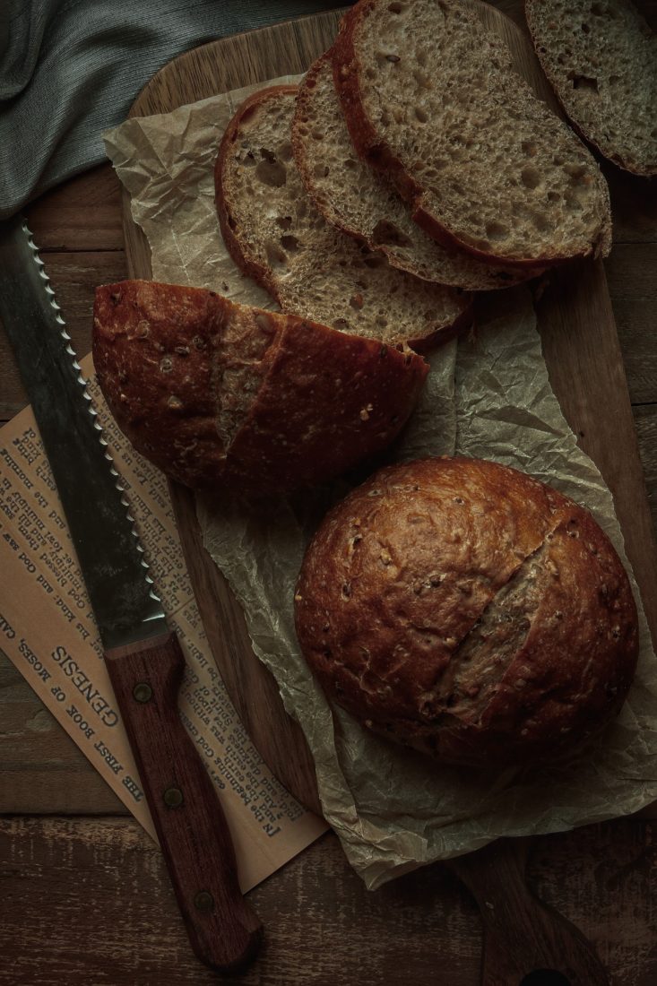 A round sourdough loaf and slices on a wooden board
